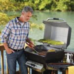A man making food on a stainless steel gas grill.