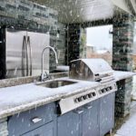 An outdoor kitchen in the snow, with a layer of snow on top of the scene