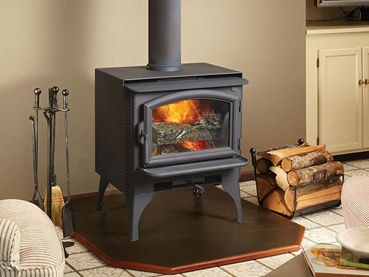 black wood stove with logs next to fire