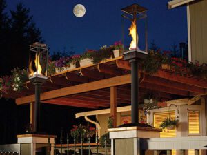 The flames inside two Tempest Torches dance on an outdoor patio.