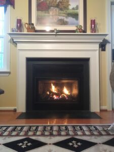 An elegant Mendota fireplace with a decorative mantle in a room with a patterned floor.
