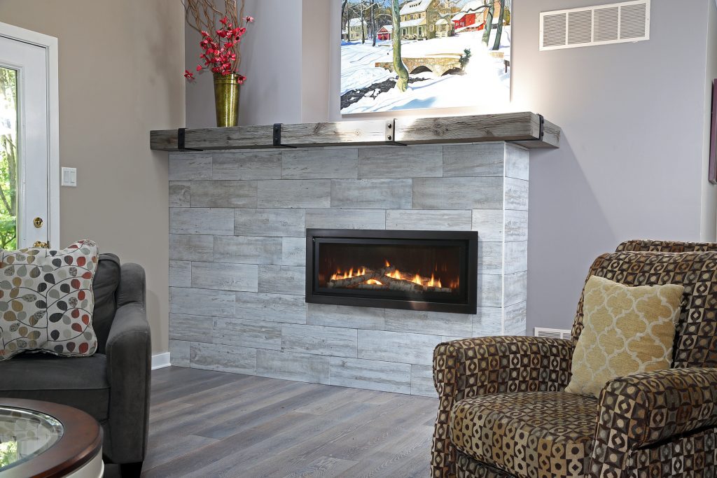A fireplace insert in a gray stone wall with a gray mantle 