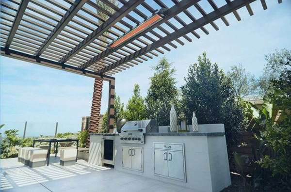 An image of an outdoor kitchen with an outdoor electric heater hanging over it.
