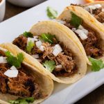 Pork carnitas tacos on corn tortillas with rice and beans